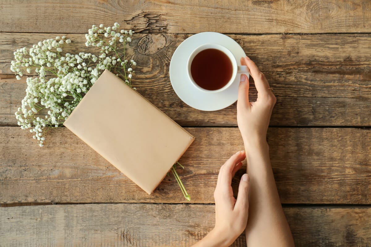 Woman with bouquet of beautiful flowers book and coffee at wood | コーヒーステーション