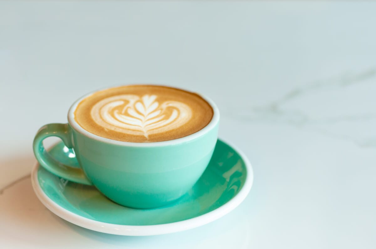 Fresh latte coffee in green cup on marble table with copy space | コーヒーステーション