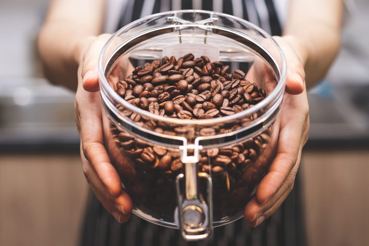 Shopkeeper woman Hold a glass jar of roasted coffee beans Conce | コーヒーステーション