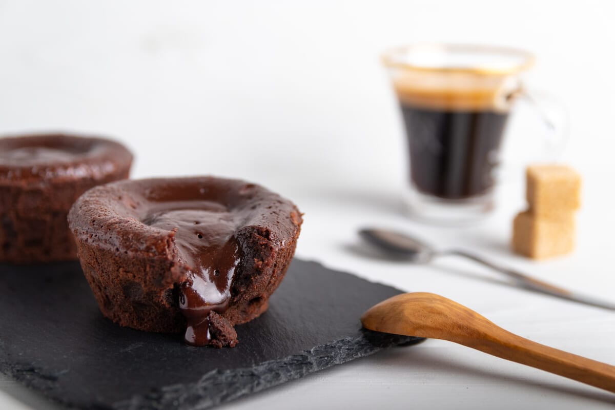 Warm chocolate lava cake on a black plate with a cup of coffee o | コーヒーステーション