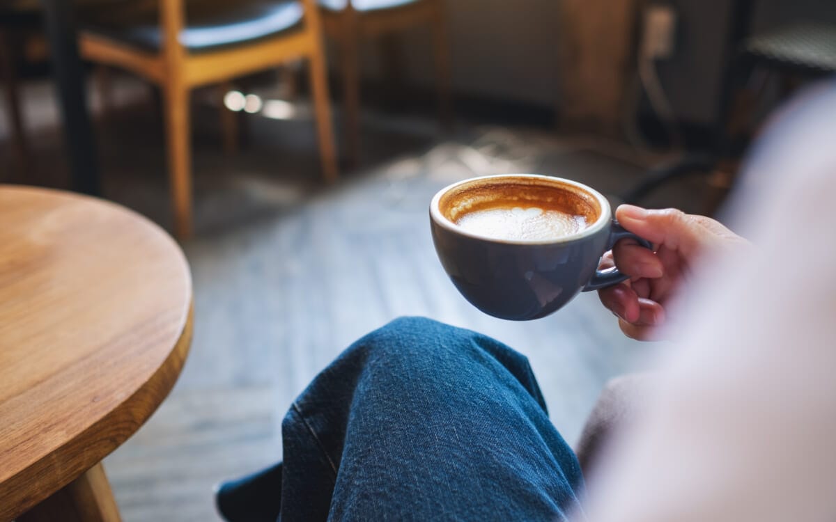 Closeup image of a woman holding and drinking hot coffee | コーヒーステーション