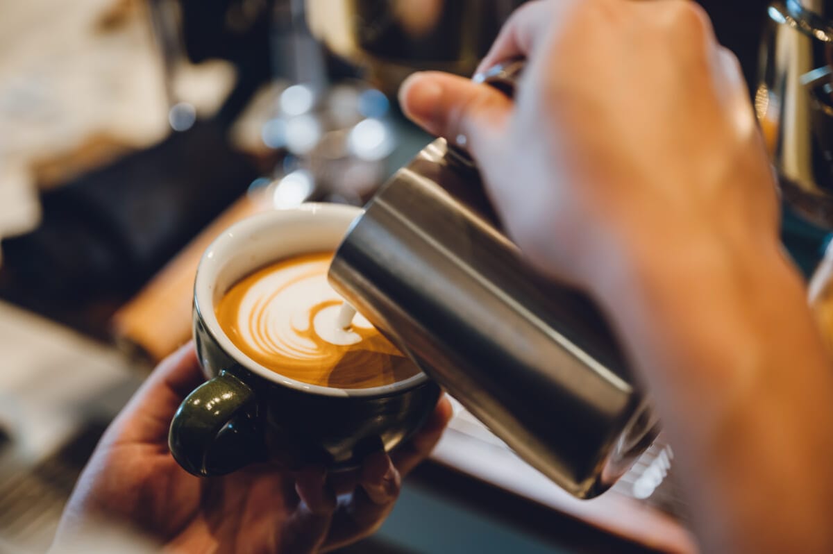 barista making latte art shot focus in cup of milk and coffee vintage filter image | コーヒーステーション
