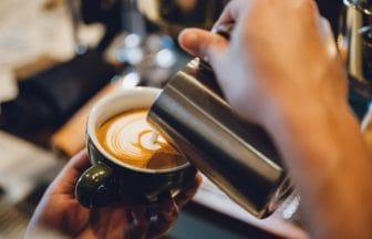 barista making latte art shot focus in cup of milk and coffee vintage filter image | コーヒーステーション