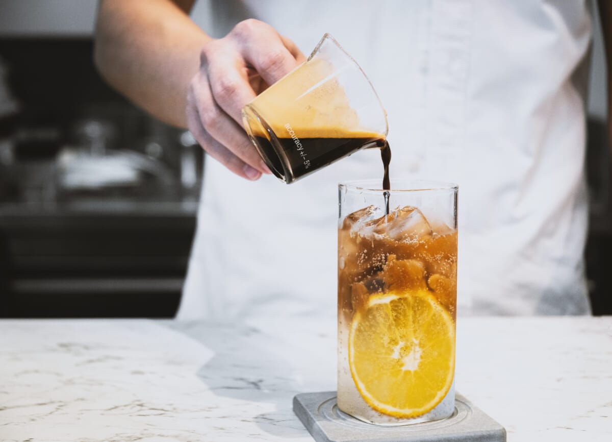 Refreshment summer drink Barista making a cold brew espresso tonic with orange on the white stone table bar | コーヒーステーション