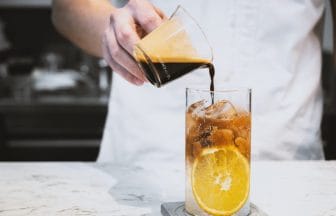 Refreshment summer drink Barista making a cold brew espresso tonic with orange on the white stone table bar | コーヒーステーション