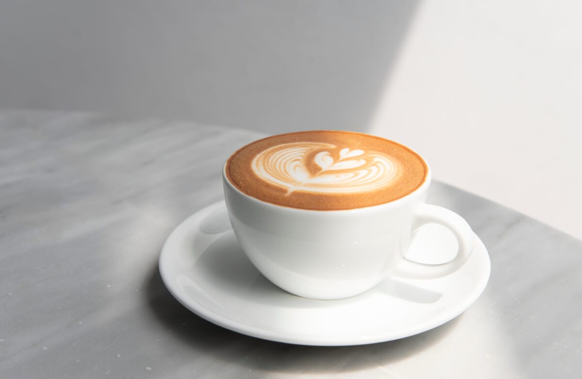 latte or Cappuccino with frothy foam coffee cup top view on tab | コーヒーステーション