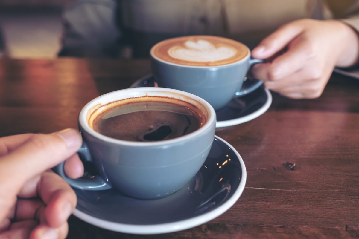 Close up image of a man and a woman clinking blue coffee mugs on | コーヒーステーション