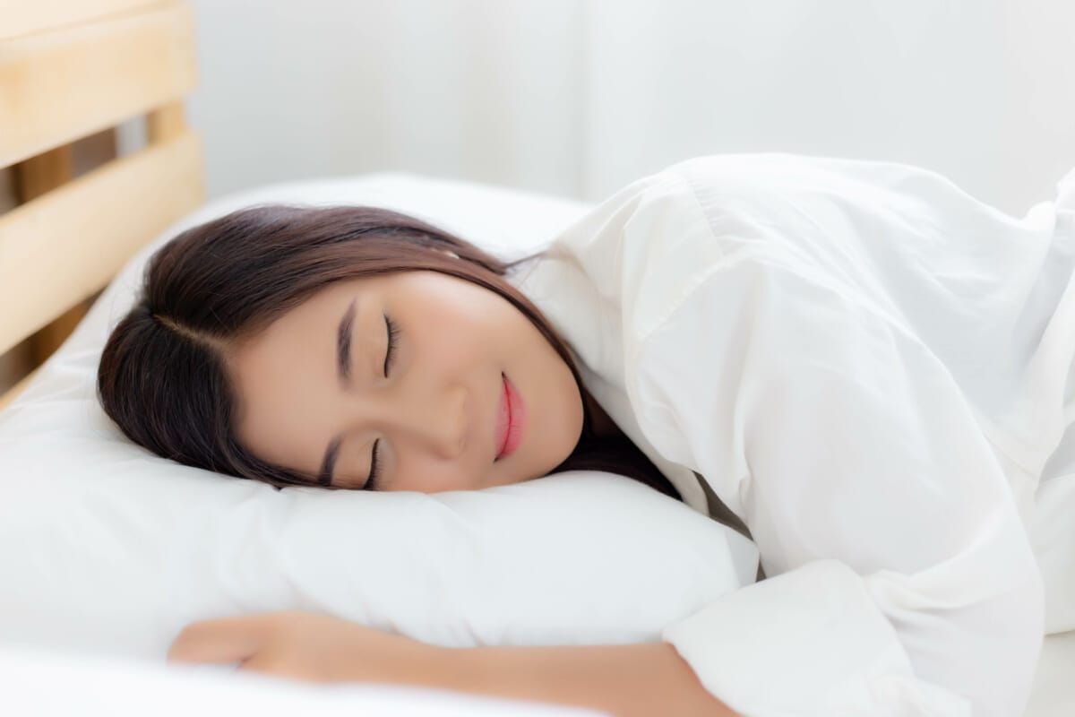 Charming beautiful woman is lying down on her bed at bedroom Glamour woman has good sleep all night on bed with smiley face Attractive beautiful girl has beautiful face with white pajamas | コーヒーステーション