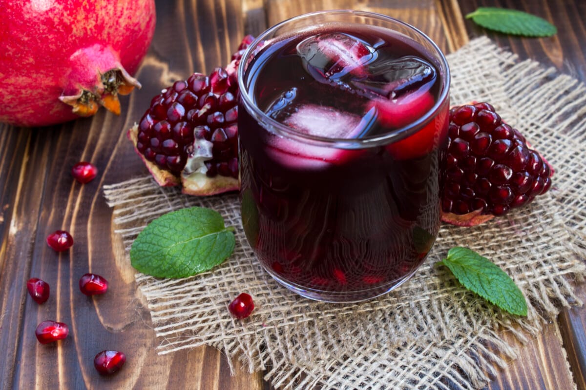 Pomegranate juice with ice in the glass on the rustic wooden background | コーヒーステーション