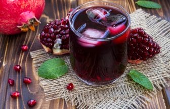 Pomegranate juice with ice in the glass on the rustic wooden background | コーヒーステーション