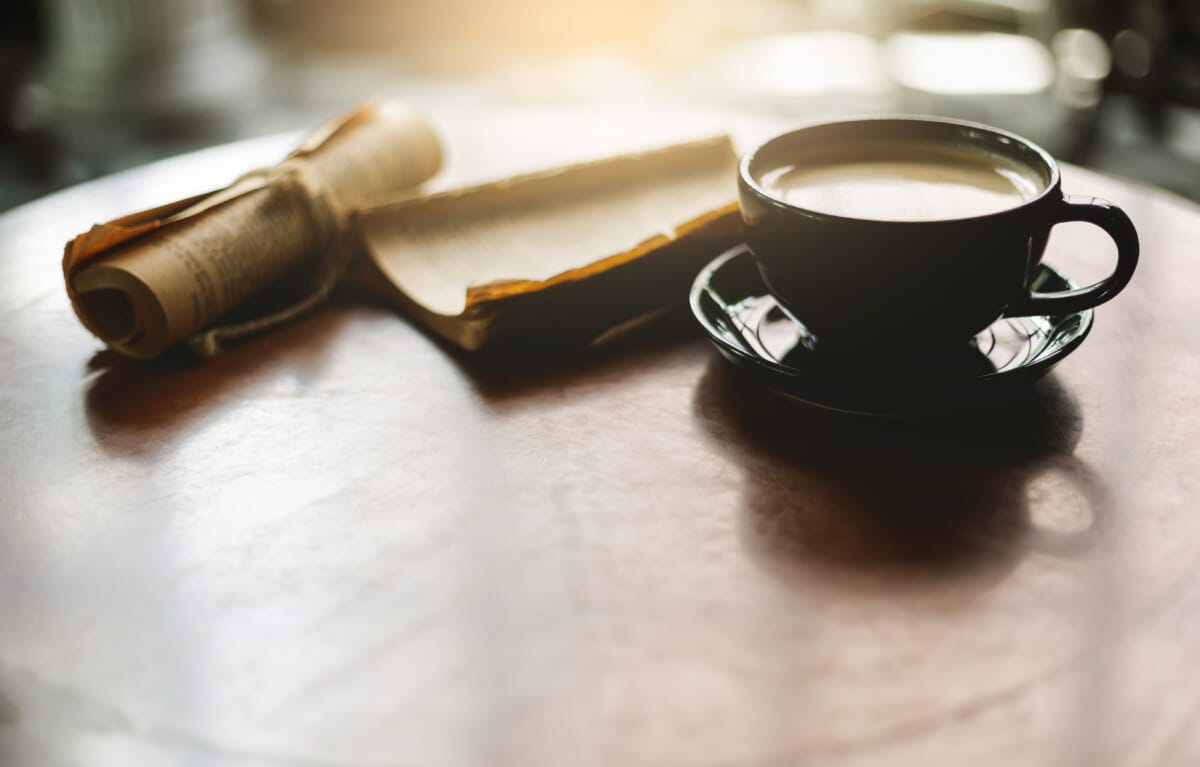 The old style of black coffee cup with old damaged book on wooden table | コーヒーステーション