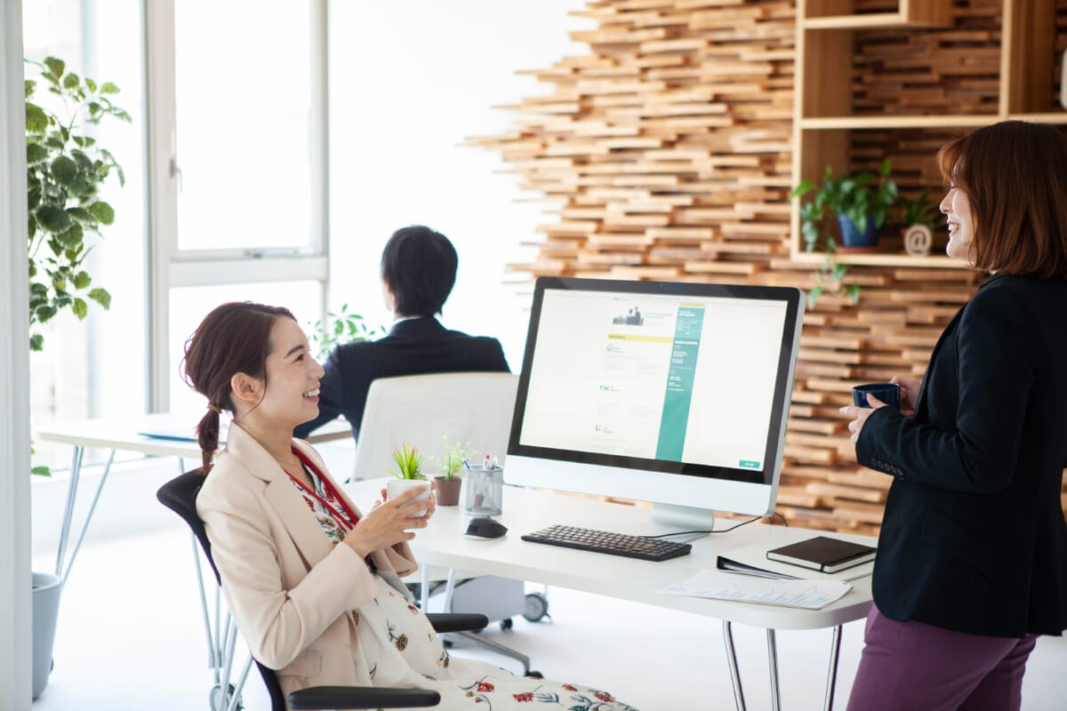 同僚との会話を楽しむ妊婦の女性社員 | コーヒーステーション