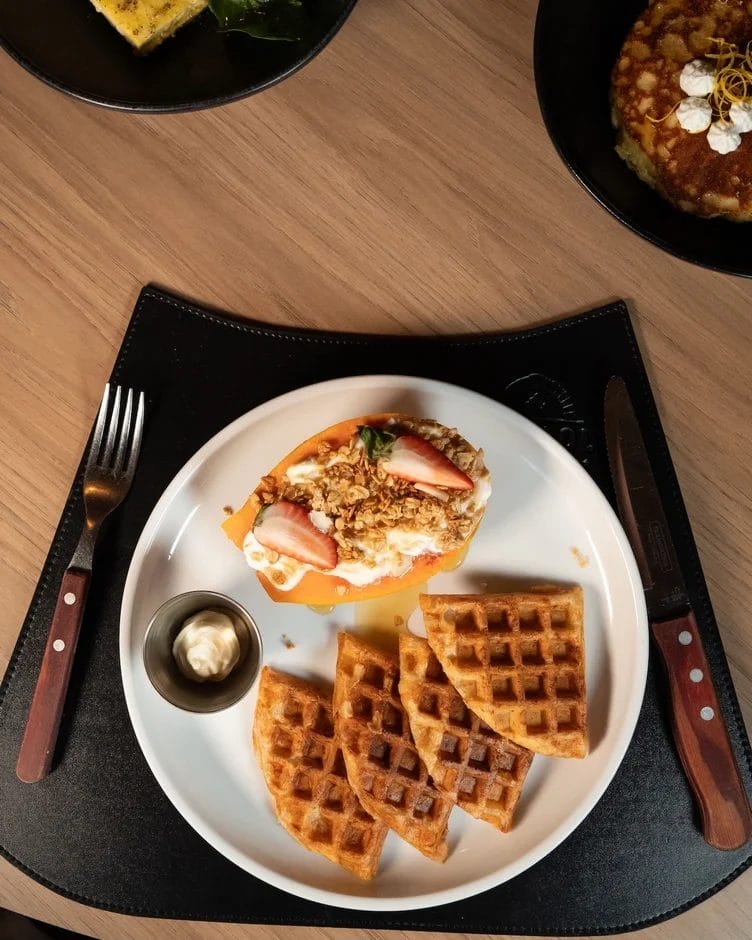 ワッフルとパパイヤにヨーグルト、グラノーラ、イチゴが添えられた朝食